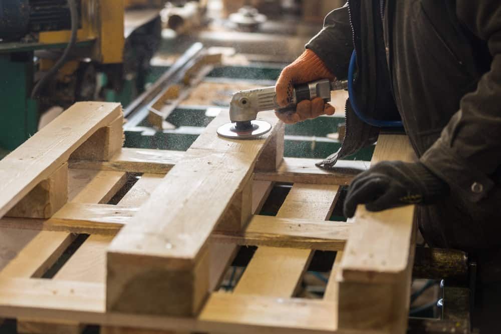 a man is grinding a wooden pallet with a grinder