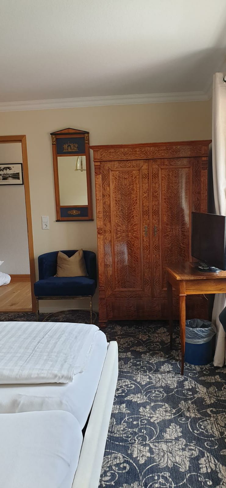 Ein Hotelzimmer mit Bett, Schreibtisch, Fernseher und Kleiderschrank.