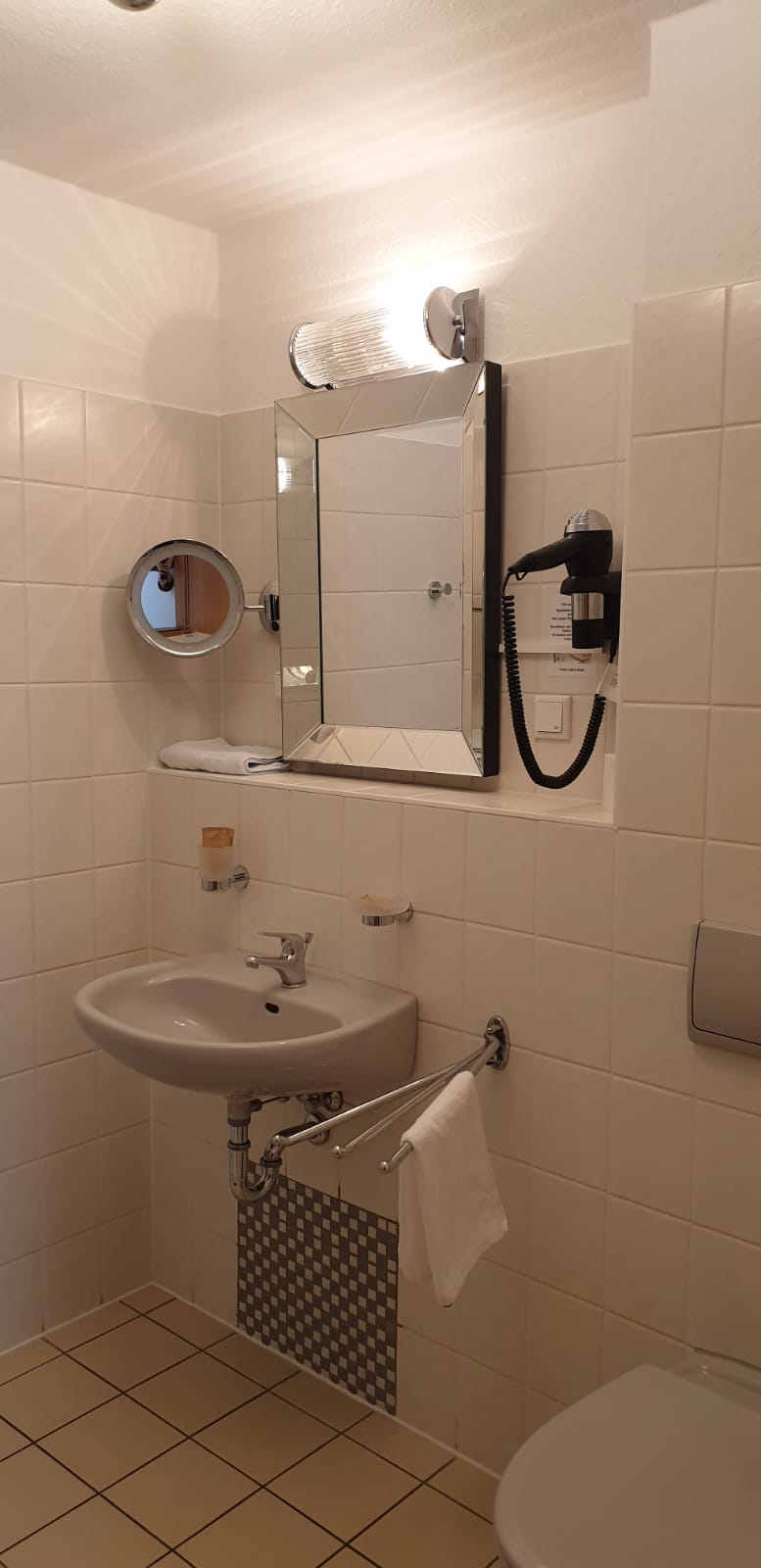 Ein Badezimmer mit Waschbecken, Toilette, Spiegel und Haartrockner.