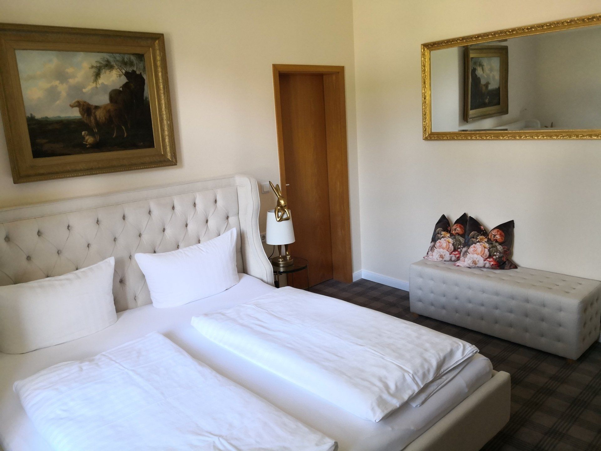 Ein Schlafzimmer mit Bett, Spiegel und Gemälde an der Wand.