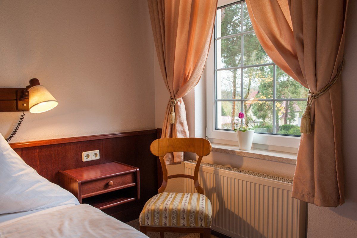 Ein Schlafzimmer mit einem Bett und einem Stuhl vor einem Fenster.