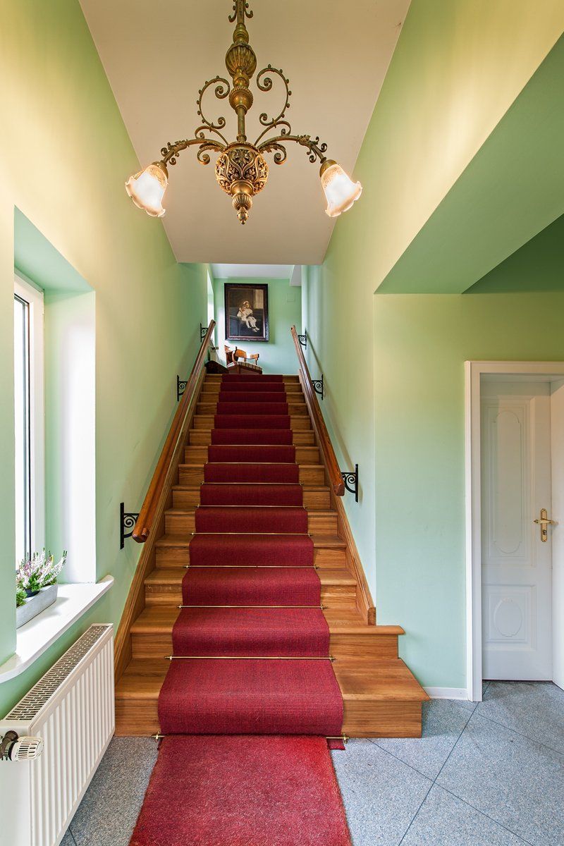 Eine Treppe mit einem roten Teppich und einem Kronleuchter, der von der Decke hängt.