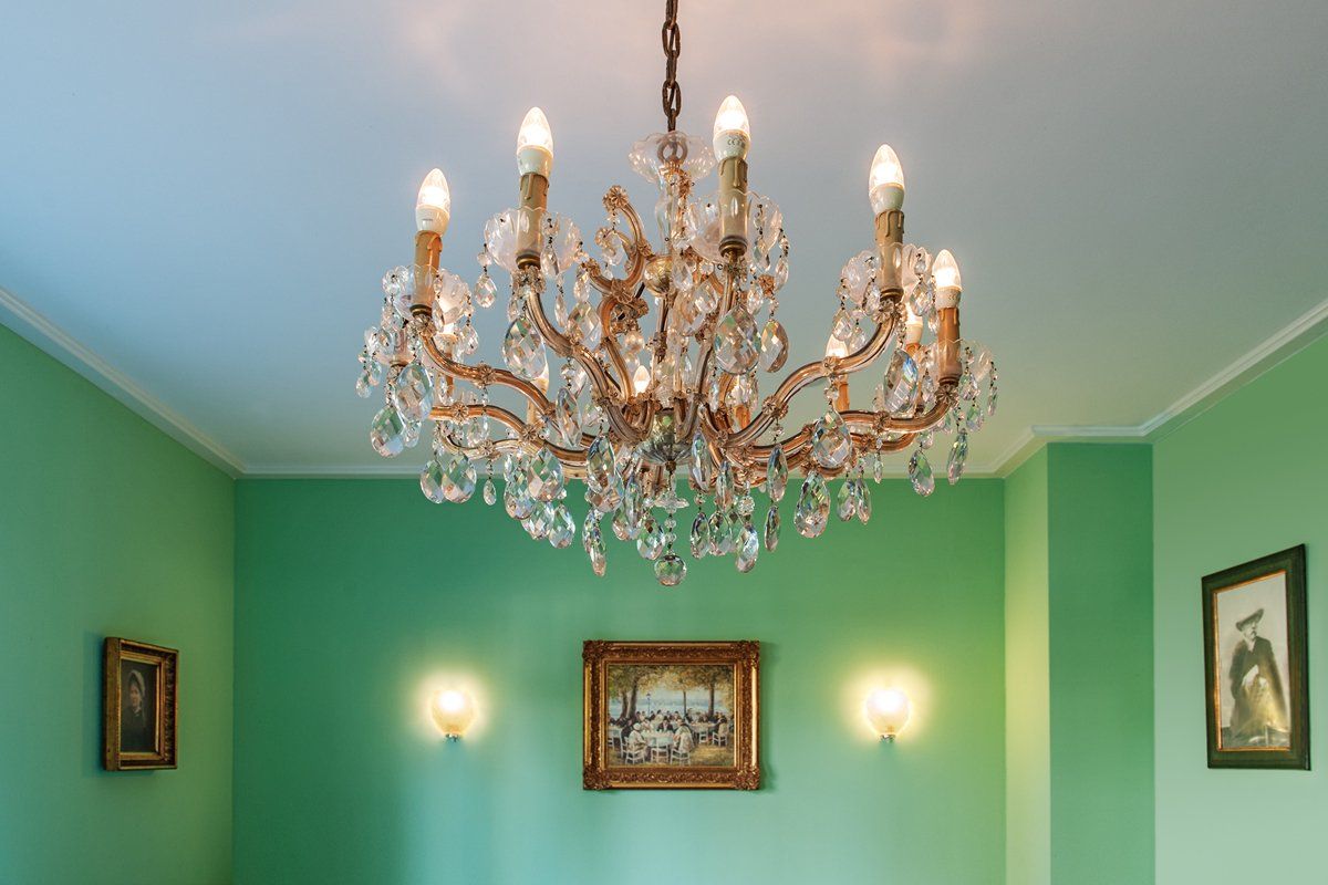 In einem Raum mit grünen Wänden hängt ein Kronleuchter von der Decke.