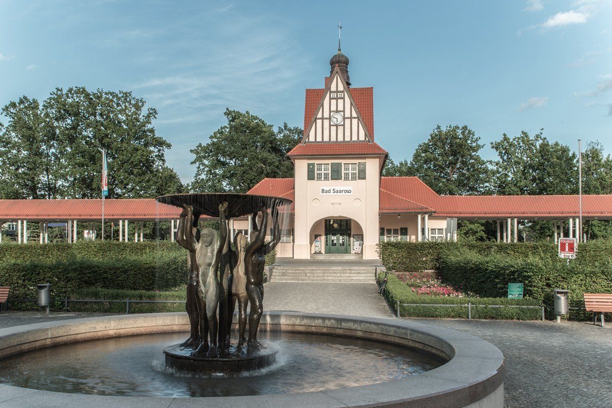 Ein Brunnen vor einem Gebäude mit rotem Dach.