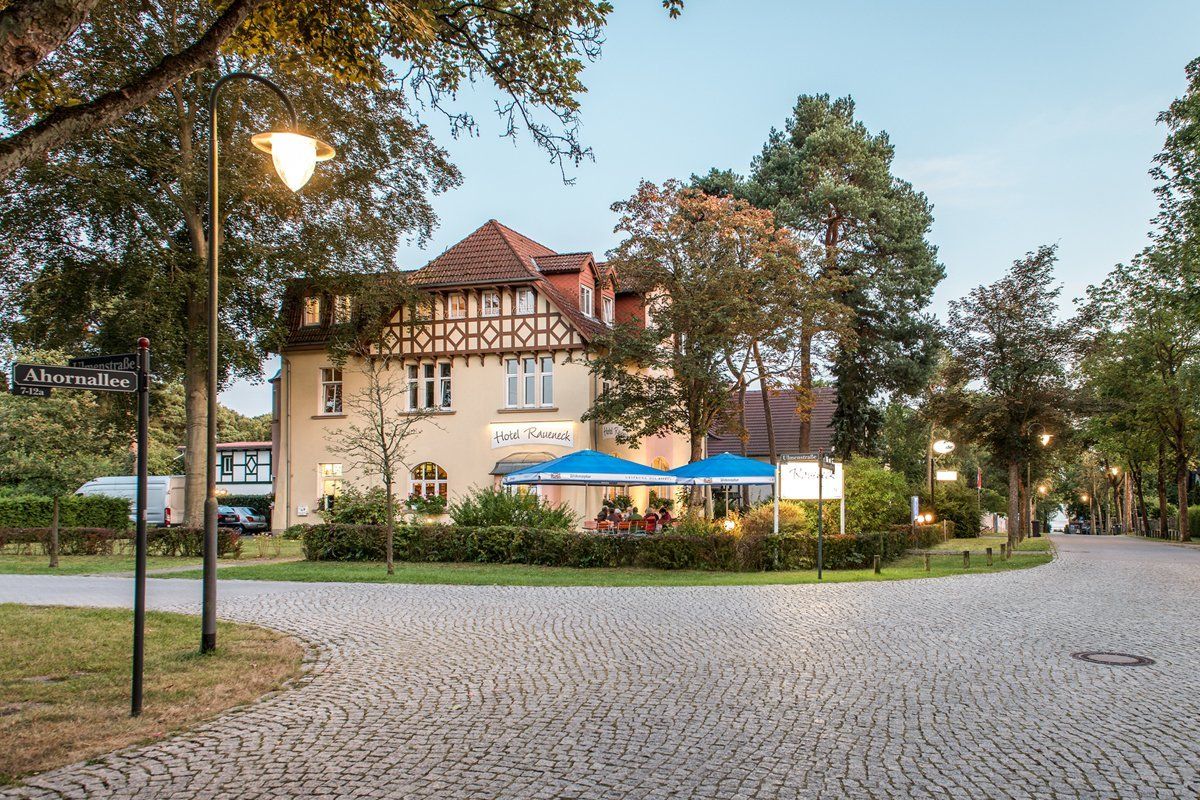 Ein großes Haus ist von Bäumen und einer Kopfsteinpflasterstraße umgeben.