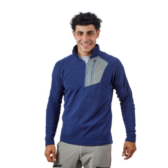 Hombre vestido con un forro polar negro con detalles rojos y pantalones grises, sonriendo.