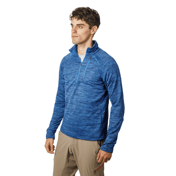 Hombre con sudadera azul con cremallera y pantalones caqui, mirando hacia la izquierda. Fondo blanco.