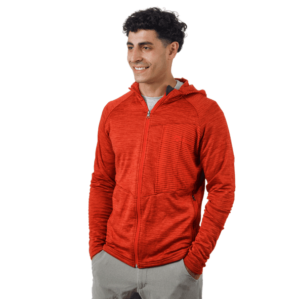 Hombre sonriente con sudadera roja con capucha y cremallera. Pantalones grises, fondo blanco.