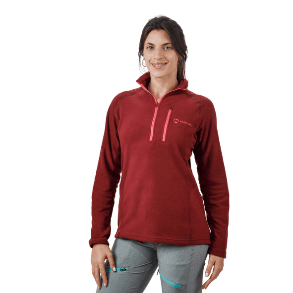 Mujer de pie, vestida con un forro polar negro con media cremallera y pantalones grises.