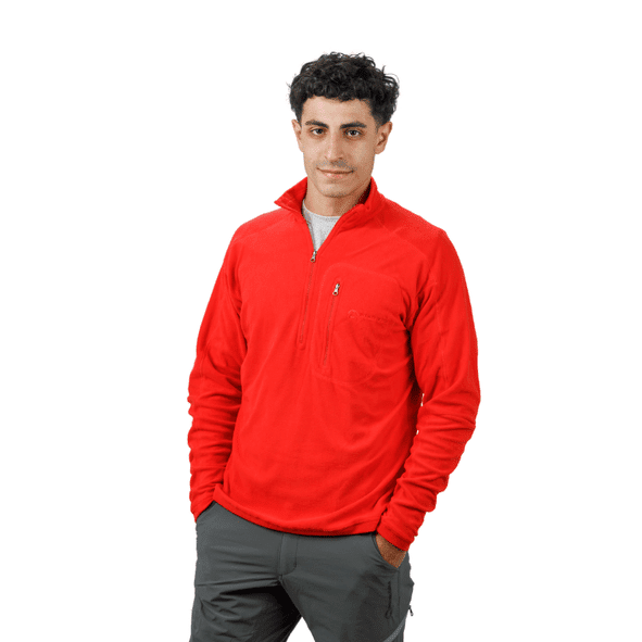 Hombre con camisa polar negra con cremallera, pantalones grises, sonriendo.