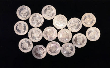 Assorted silver coins arranged in a loose cluster on a dark background