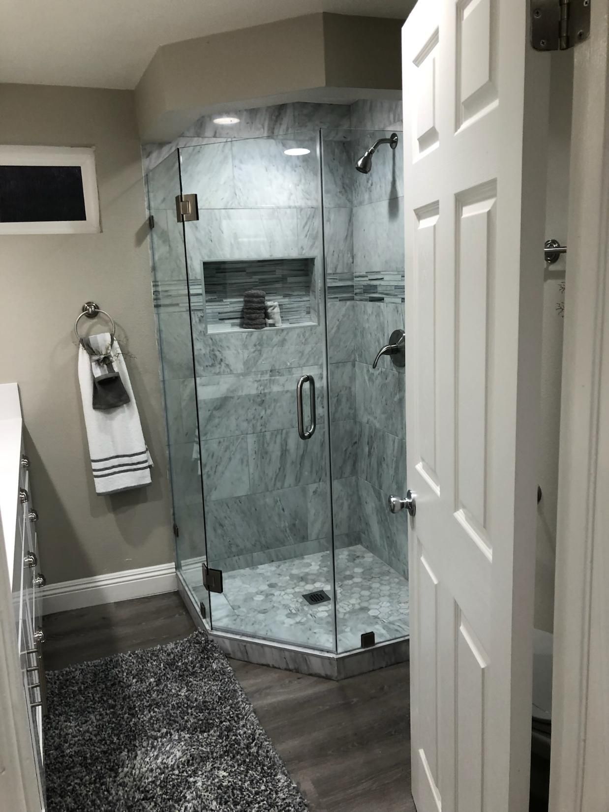 Modern bathroom with a glass shower enclosure, gray tile, and dark wood floor.