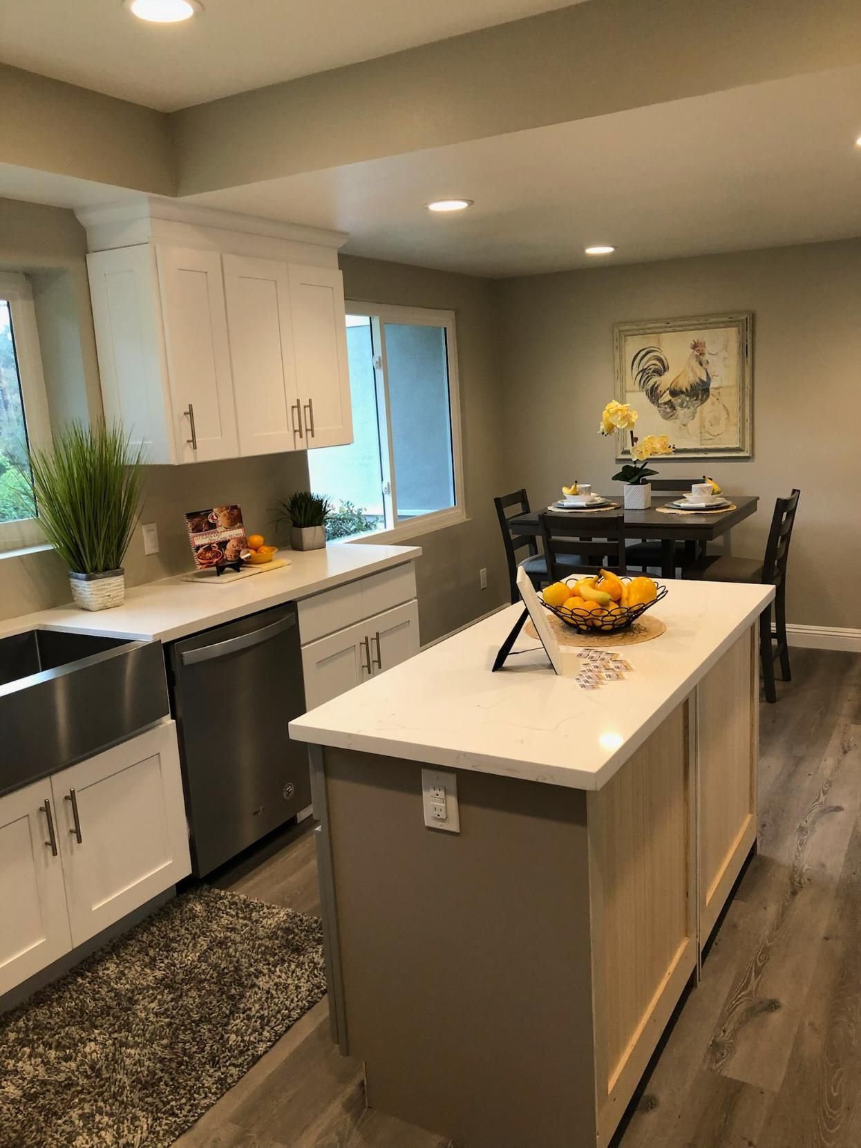 Modern kitchen with gray island, white cabinets, stainless appliances, and a fruit bowl on the counter