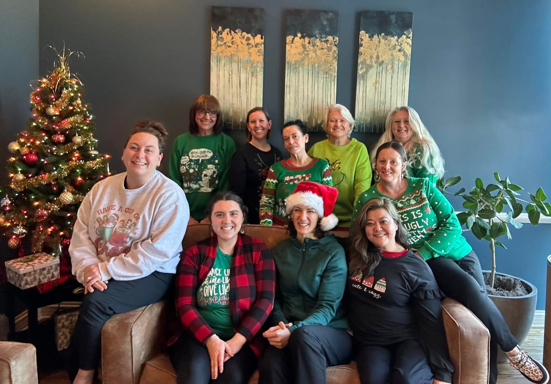 A group of women are posing for a picture in front of a christmas tree.