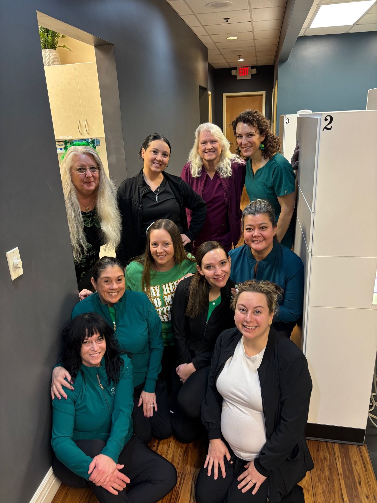 A group of women are posing for a picture in a hallway.