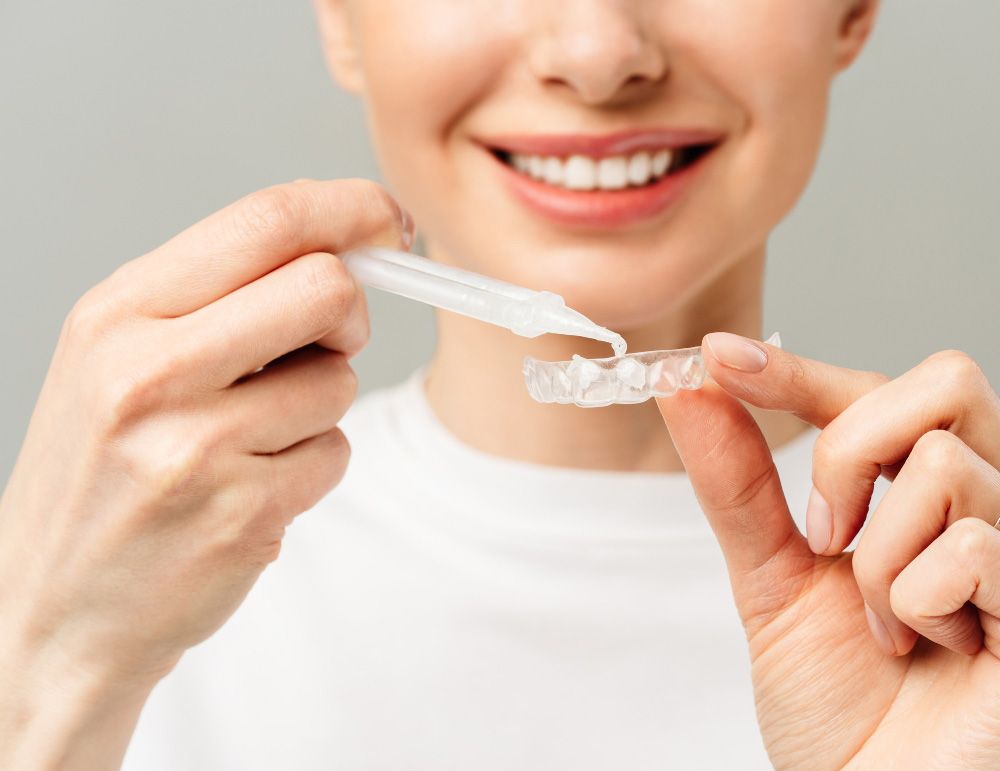 A woman is holding a whitening device in her hand.