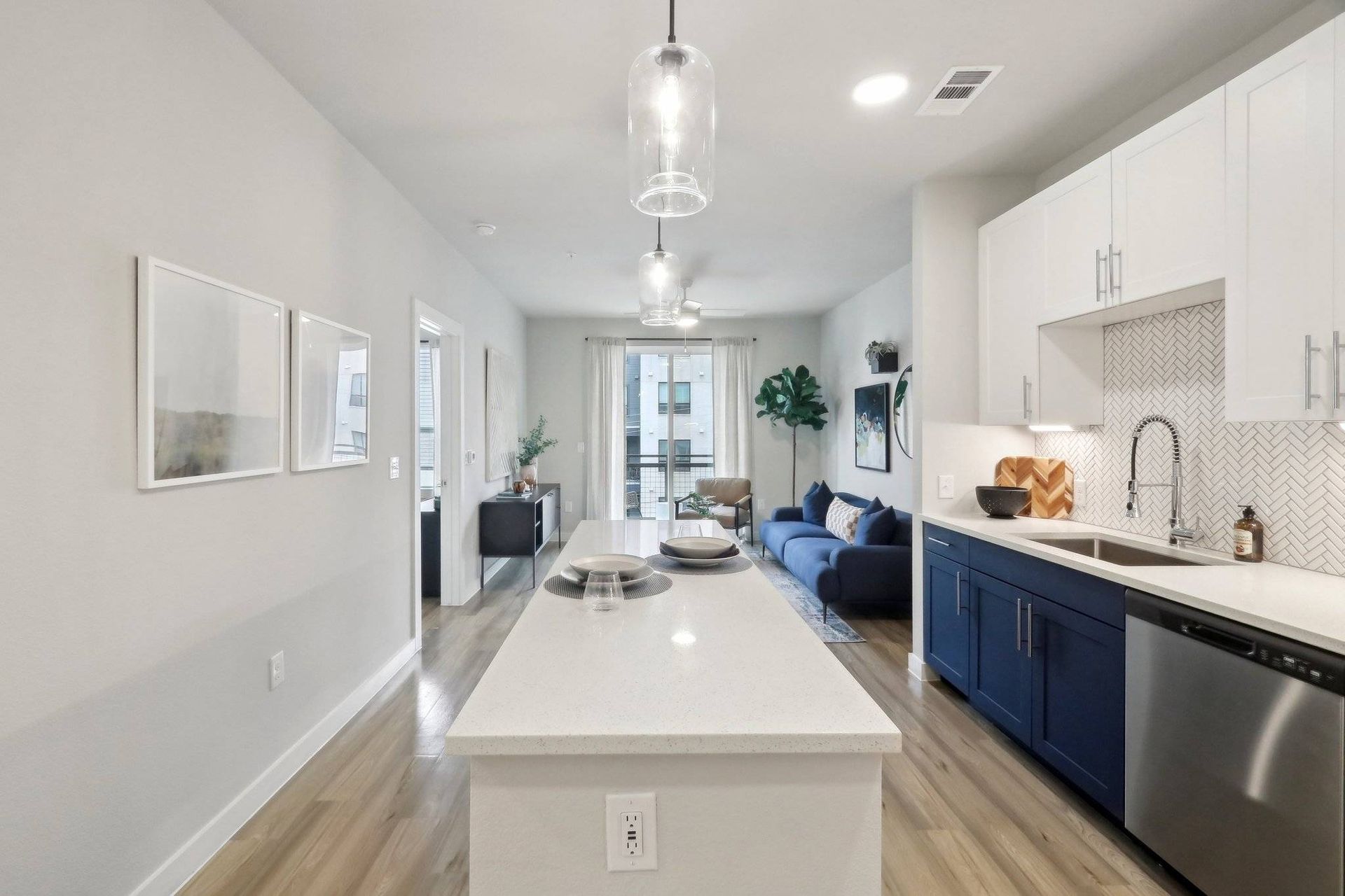 Open-concept kitchen and living area with island, white counters, and blue lower cabinets.