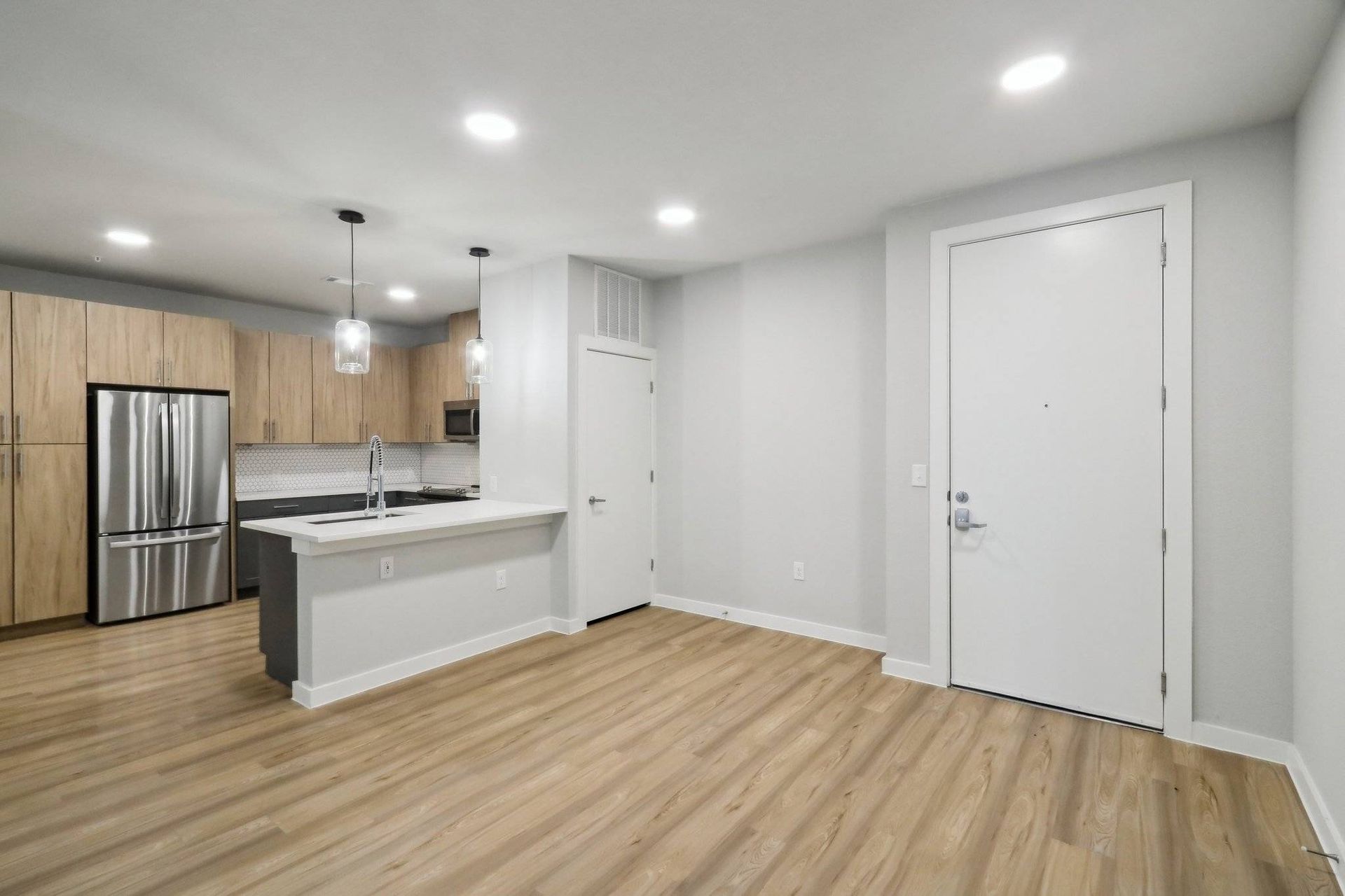 Open-concept kitchen with island, wood-tone cabinets, and stainless steel appliances.