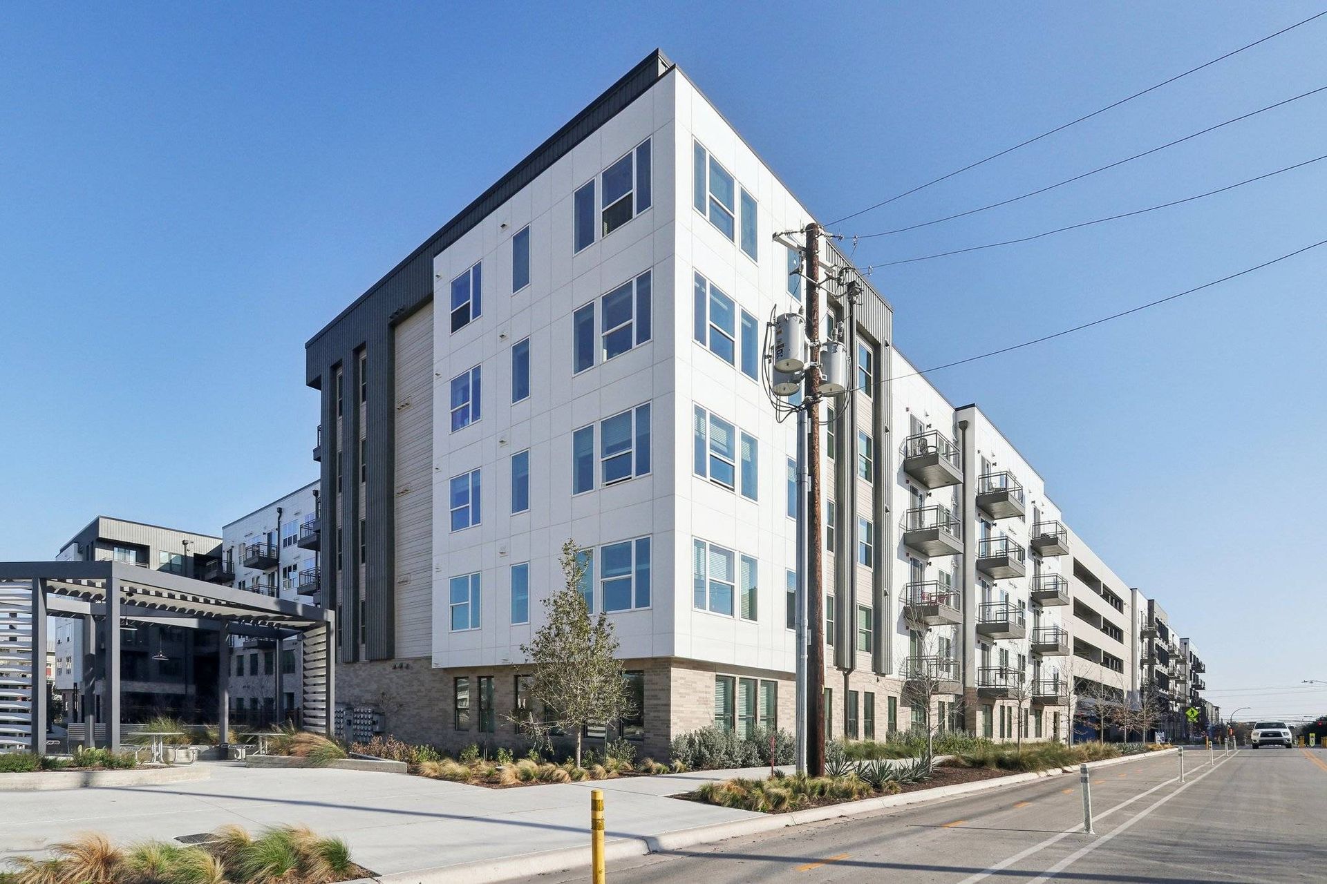 Exterior view of a modern apartment building with multiple balconies along a street.