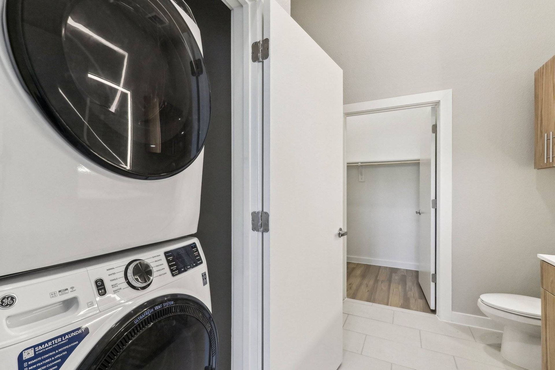 Stacked washer and dryer in a compact laundry closet beside a bathroom.