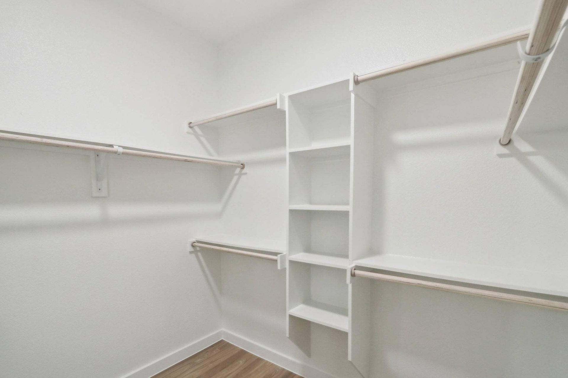 White walk-in closet with built-in shelves and hanging rods.