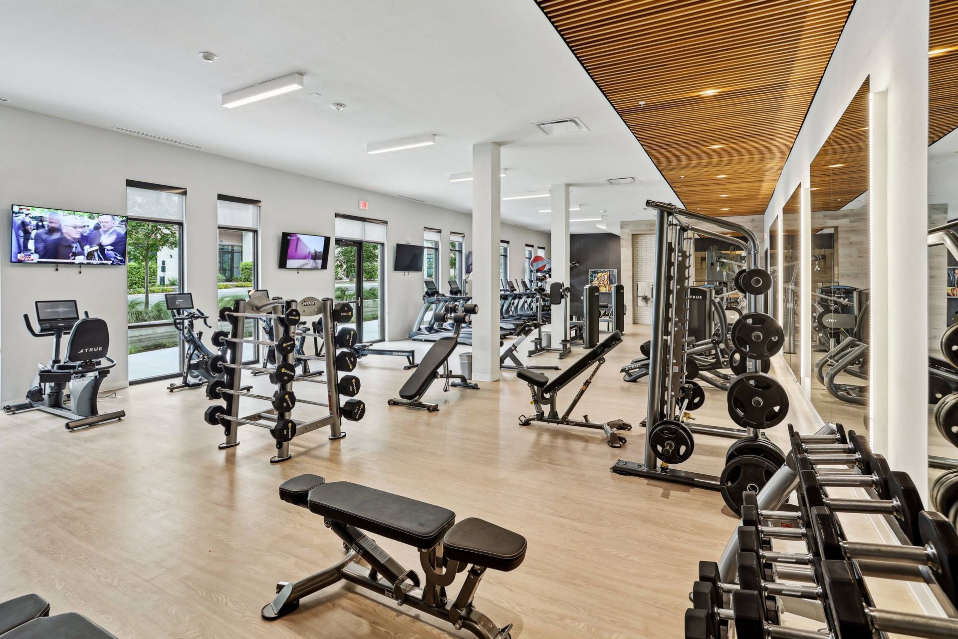 Bright modern fitness center with treadmills, weight machines, benches and mirrors.