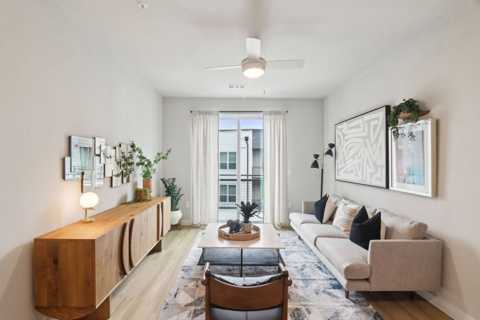 Bright living room in a modern apartment with sofa, coffee table, rug, and balcony door.