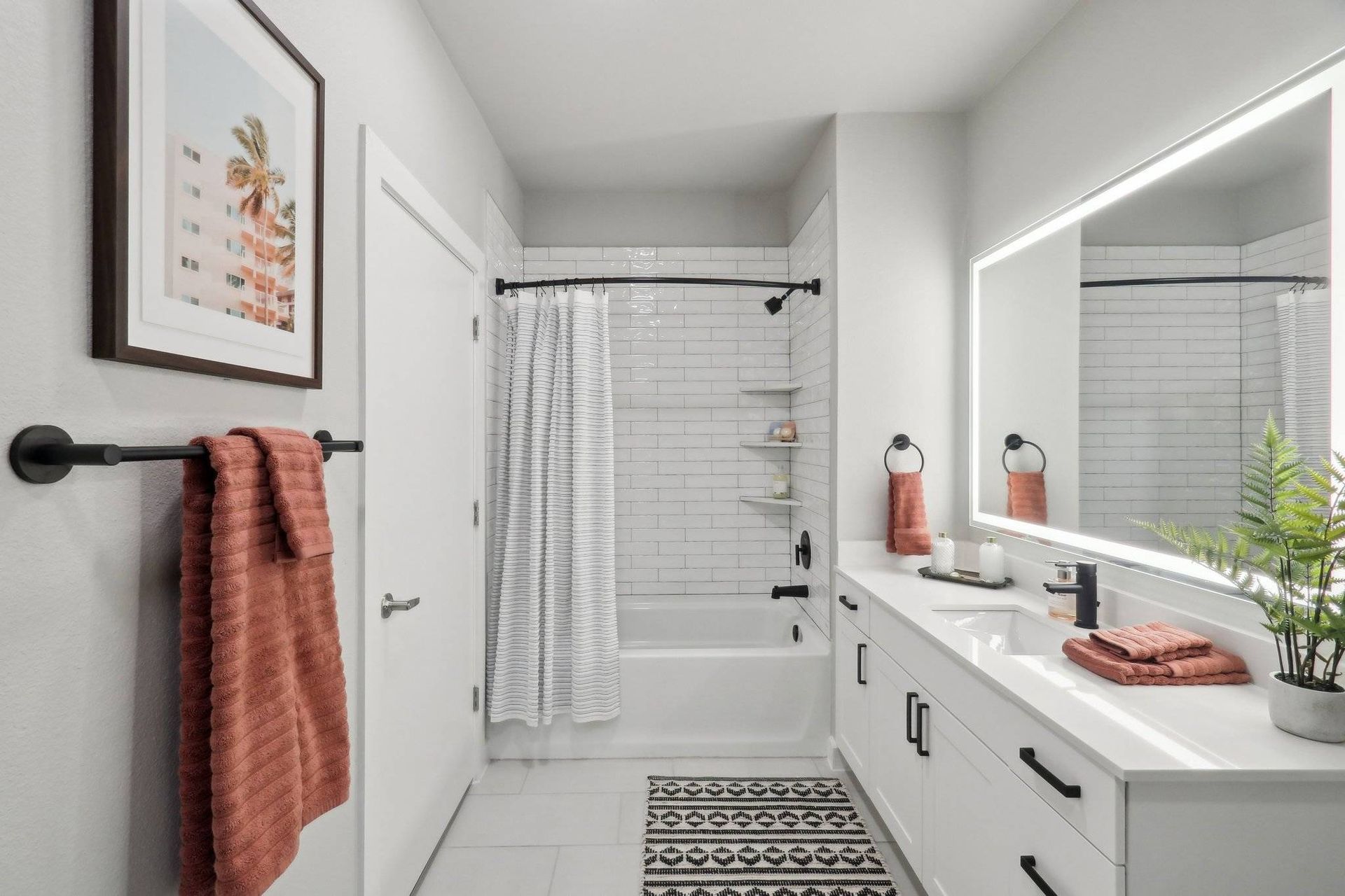 Modern apartment bathroom with white subway tile, a shower/tub, and a double vanity.