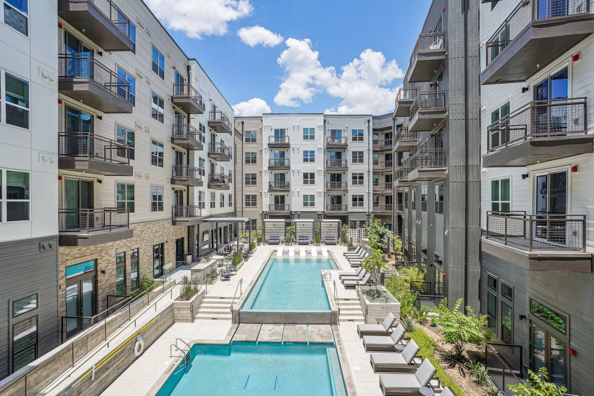 Central outdoor pool area surrounded by modern apartment buildings and balconies.
