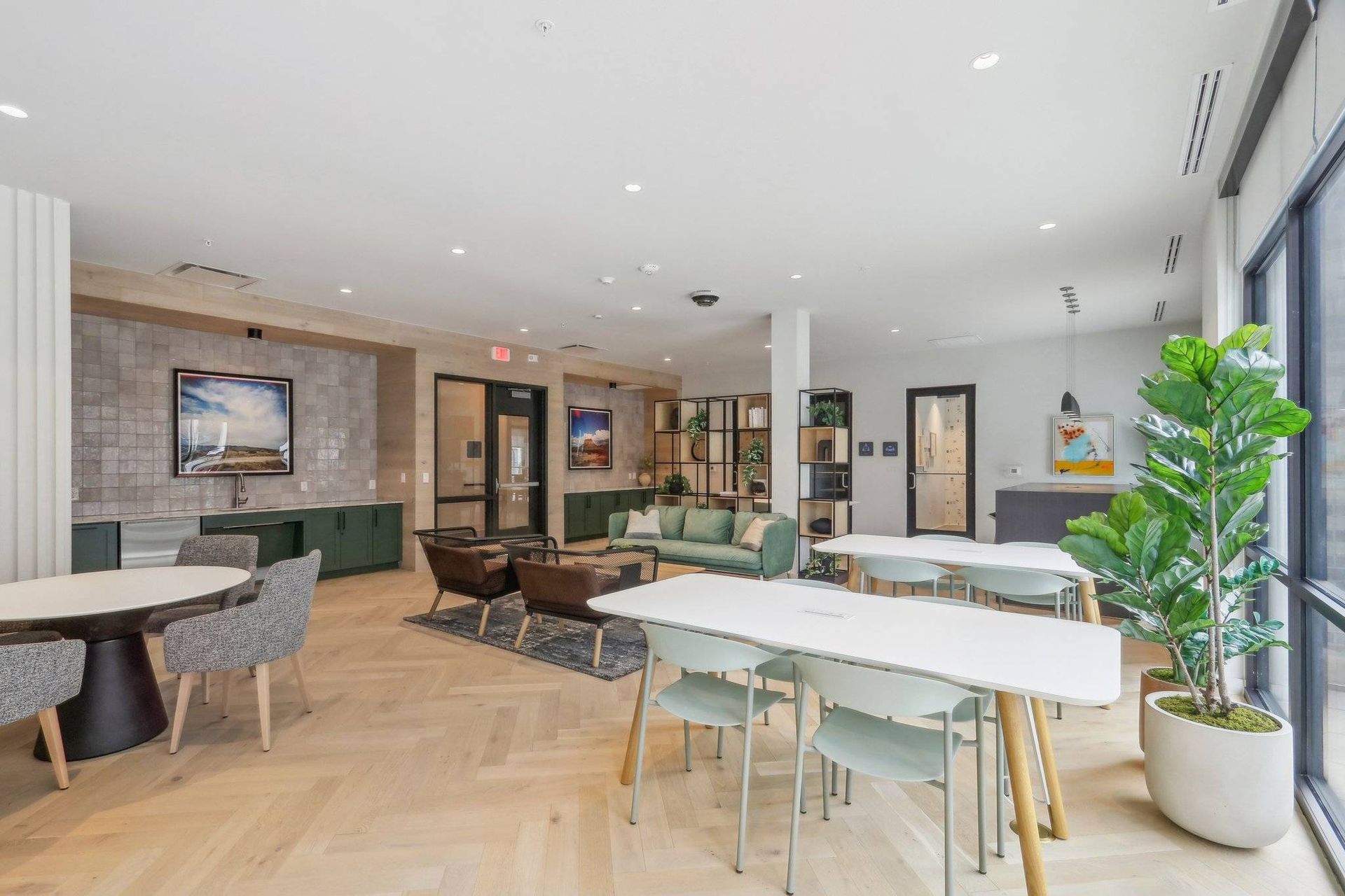 Bright communal lounge with sofas, tables, and large windows.