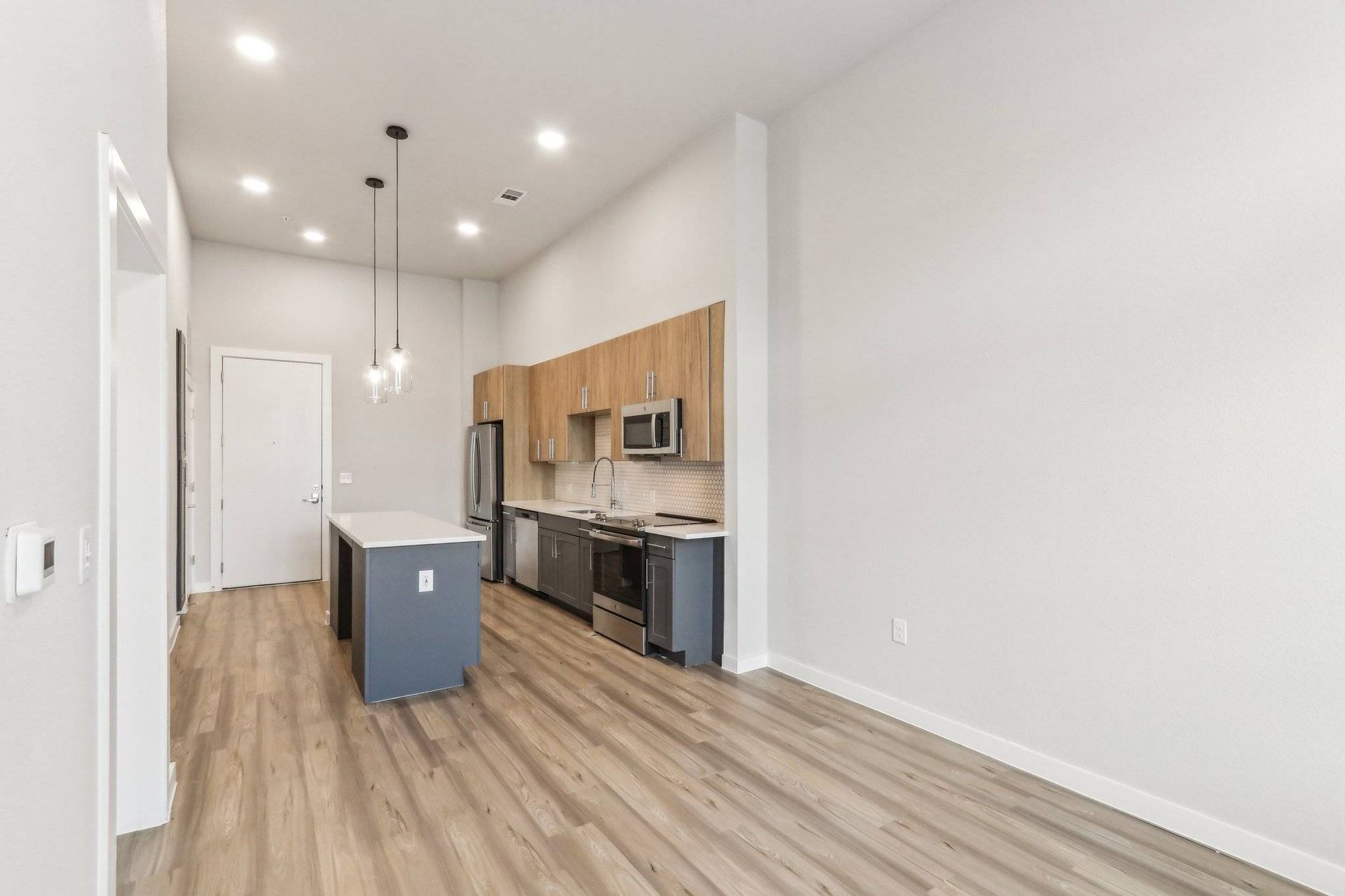 Interior view of a modern kitchen with an island, wood cabinets, and stainless steel appliances.