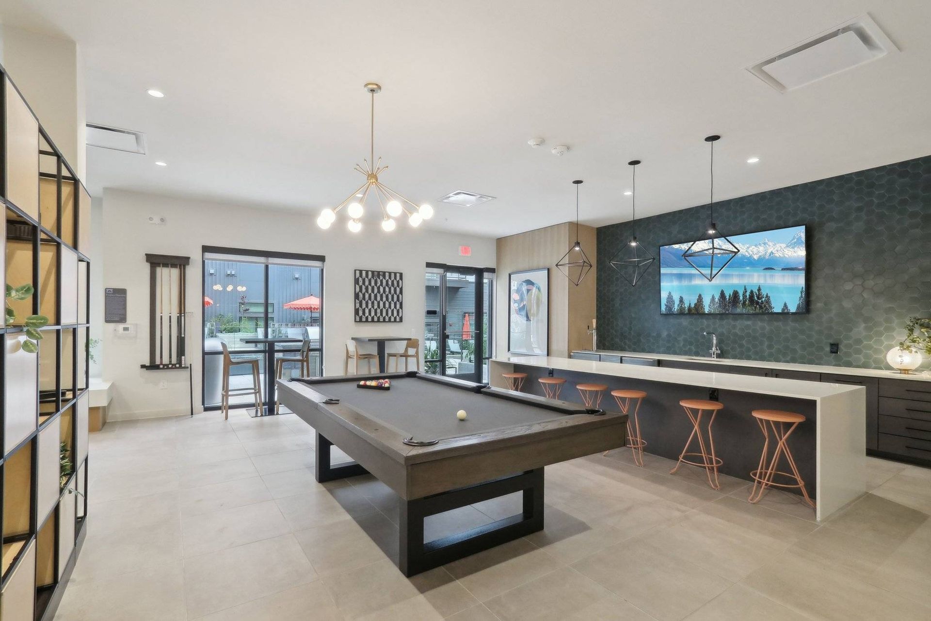 Interior communal recreation lounge with a pool table, bar seating, and a large wall-mounted TV.