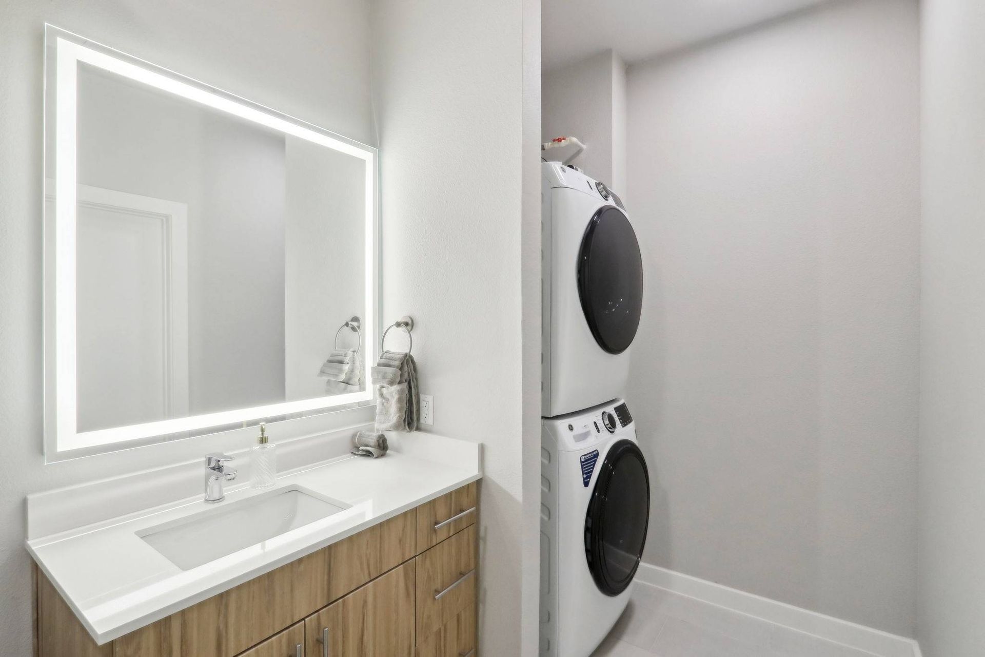 In-unit laundry area with stacked washer and dryer beside a modern vanity.