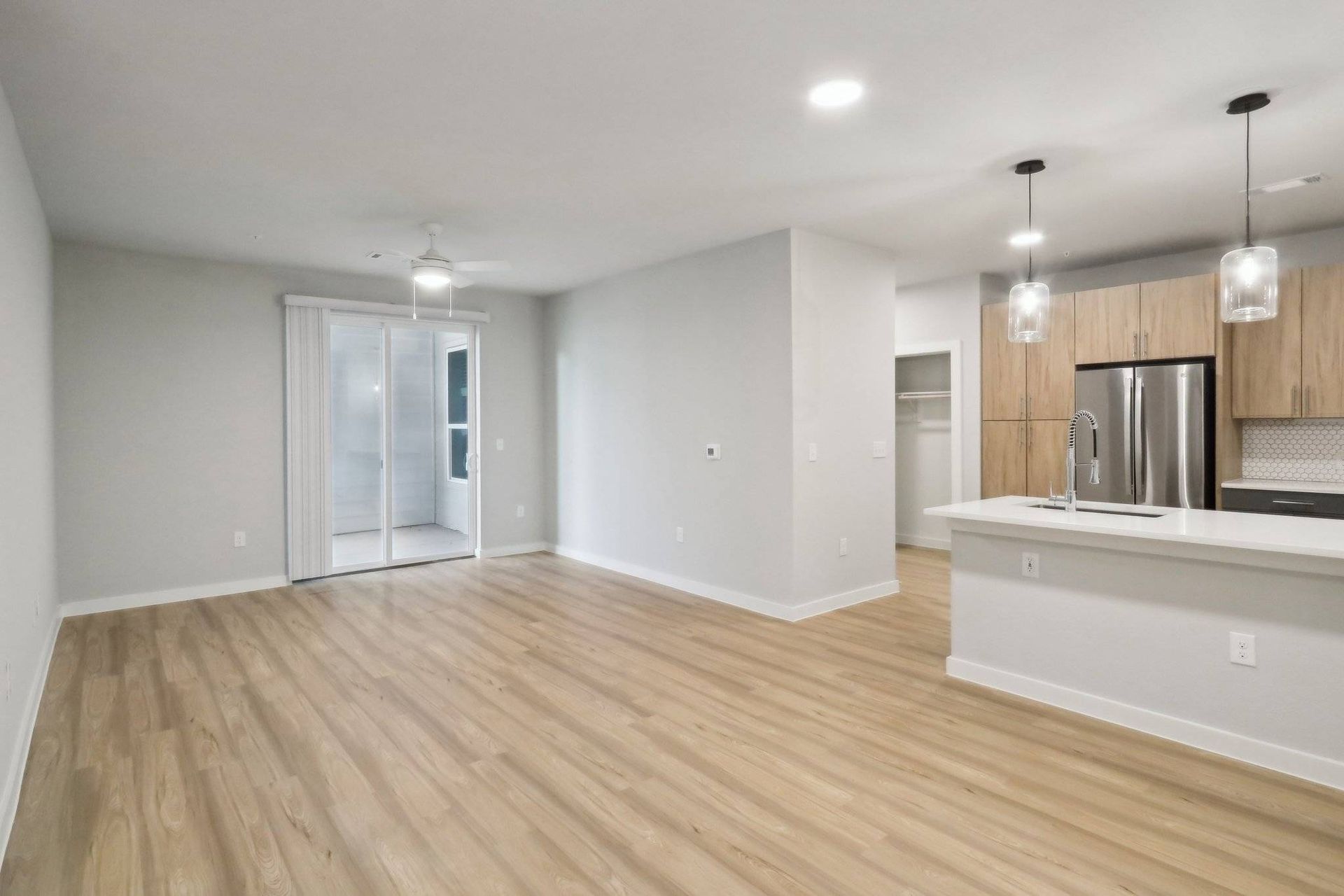 Open living area with hardwood floors, sliding balcony door, and modern kitchen.