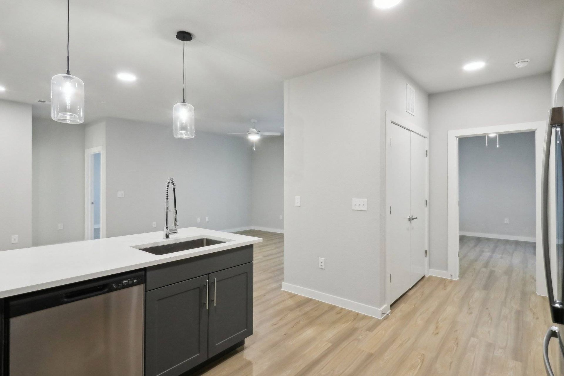 Open-concept kitchen with an island, stainless sink, and dishwasher in a modern apartment.