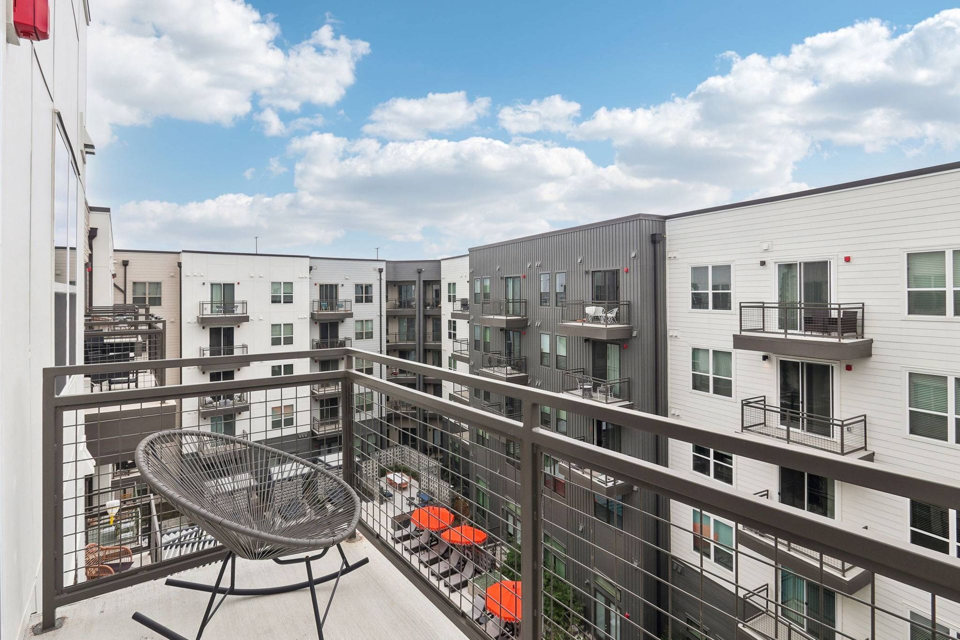 Balcony view overlooking a modern apartment complex with multiple buildings and a shared courtyard.