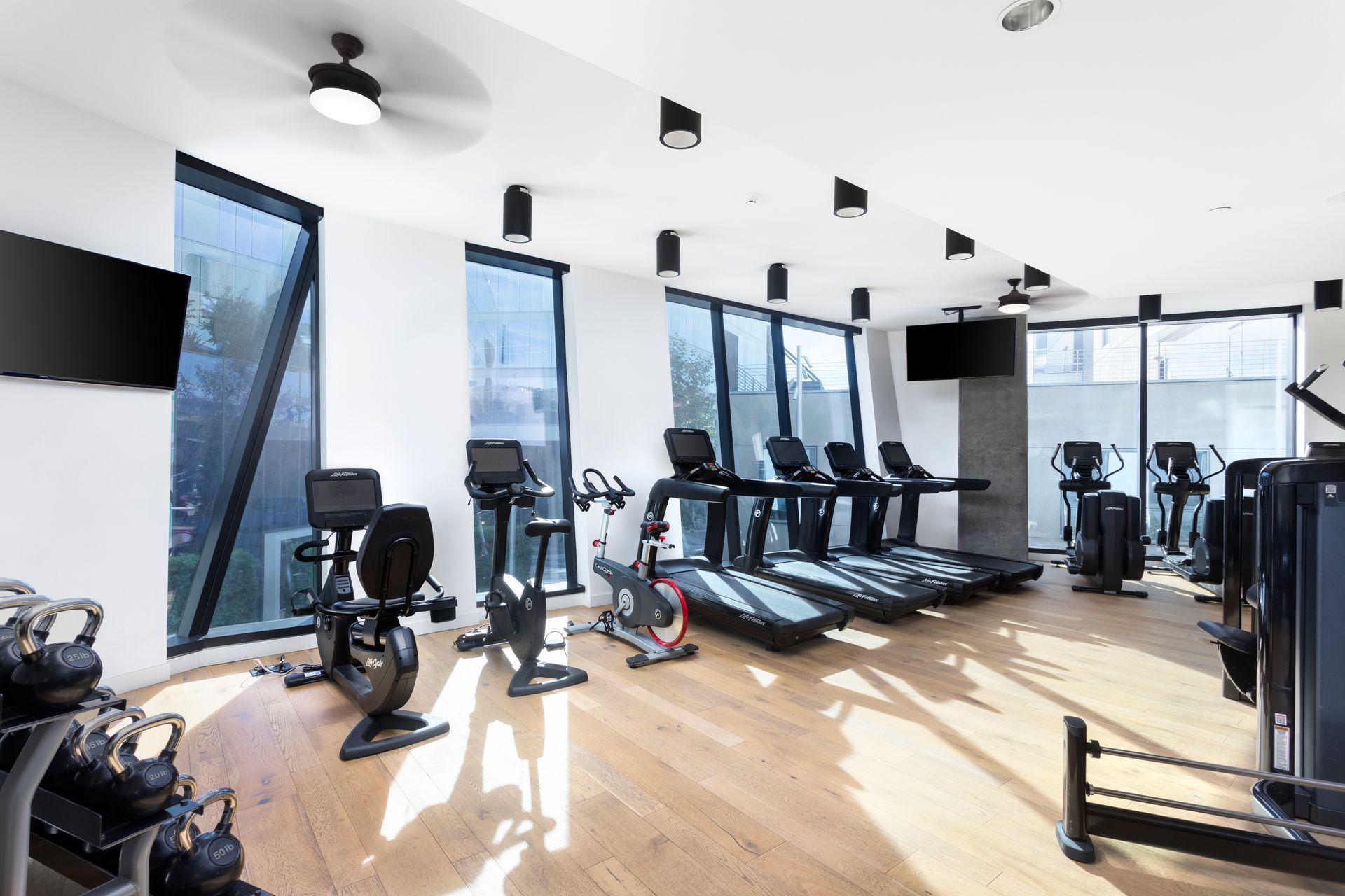 Bright modern gym with treadmills, exercise bikes, and large windows