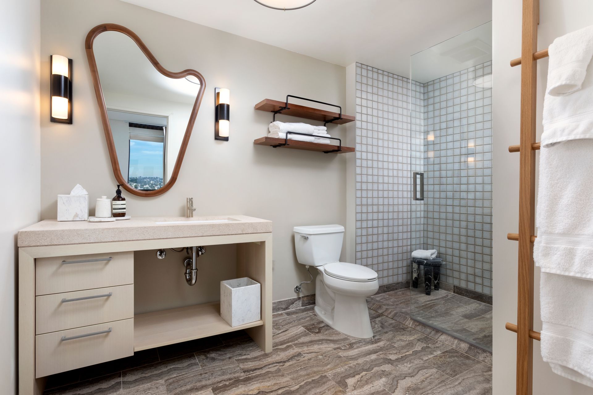 Modern bathroom with vanity, mirror, toilet, and glass shower in neutral tones