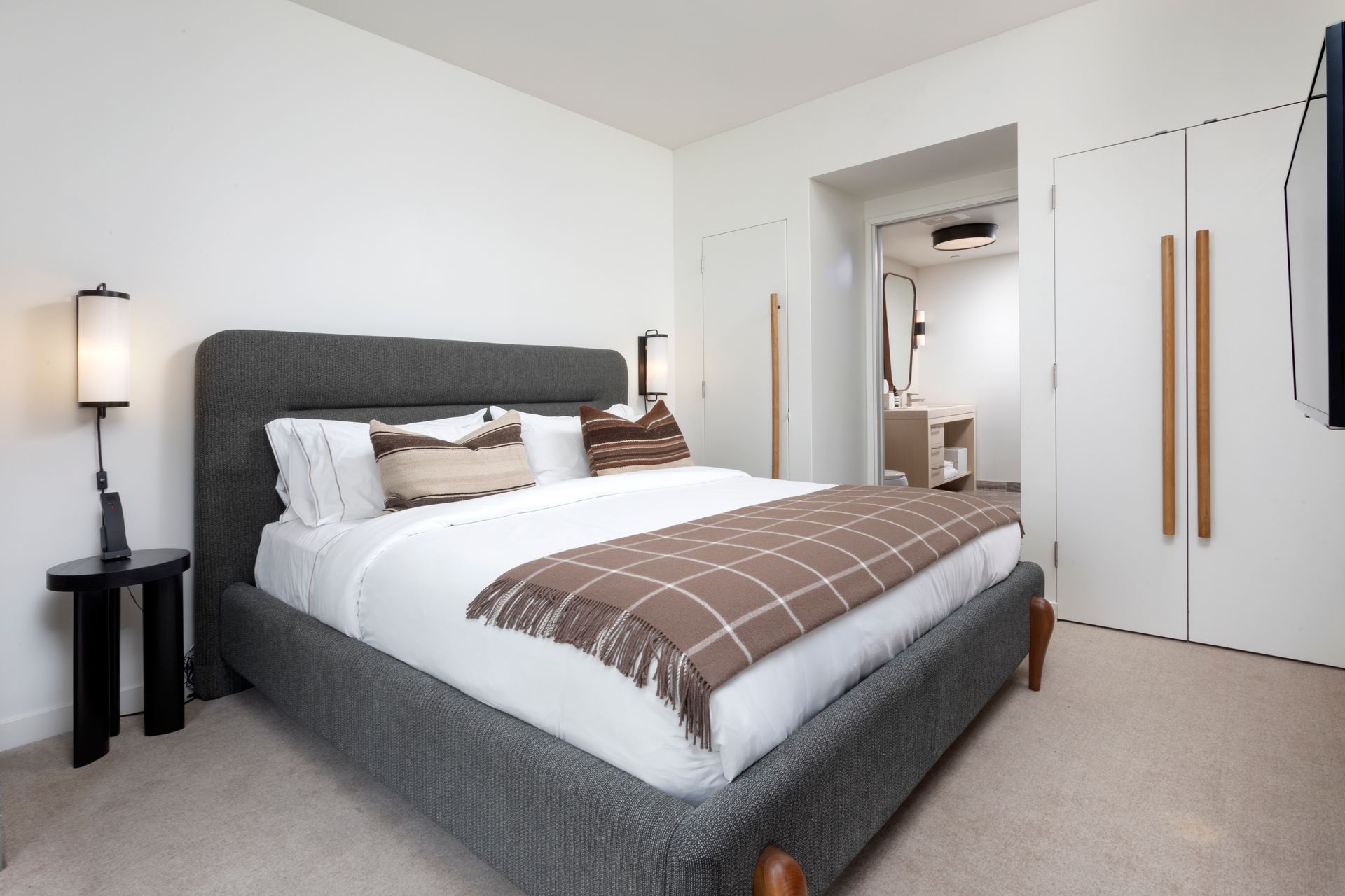 Bright modern bedroom with a gray bed, white bedding, bedside lamp, and open doorway to a closet.