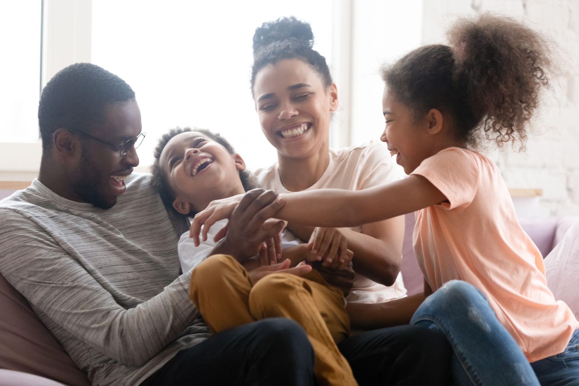 Family laughing together on a couch in a bright living room