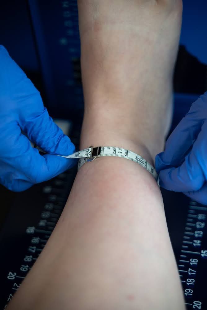 Eine Person misst ihren Knöchel mit einem Maßband