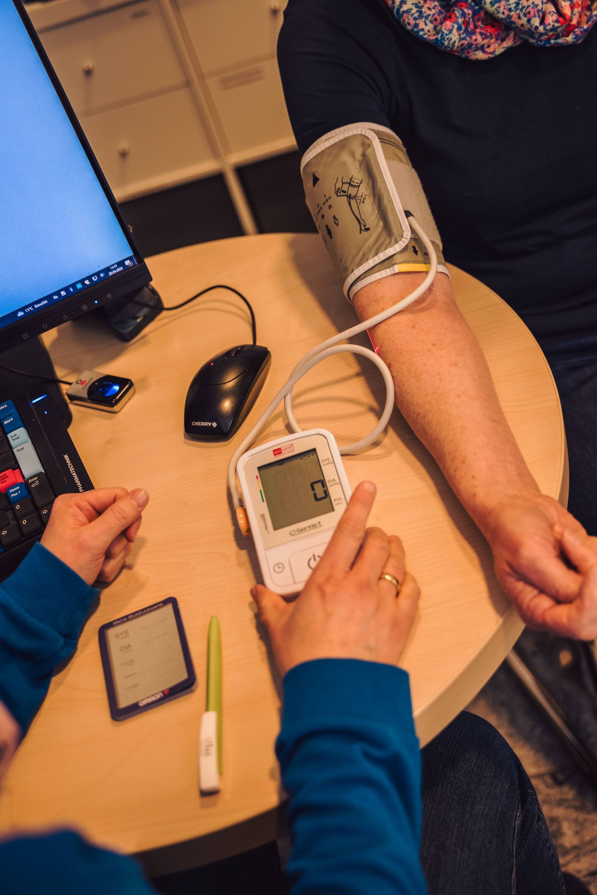 Blutdruckmessung an einem Tisch mit einem digitalen Gerät