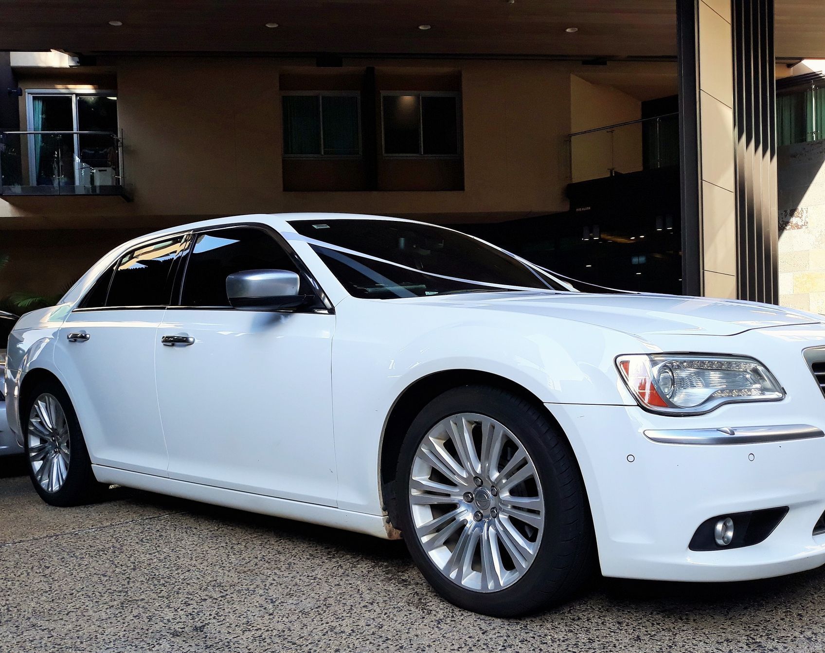 Man and a Woman Are Standing Next to a Silver Car — Territory Limousine Service in Marrara, NT