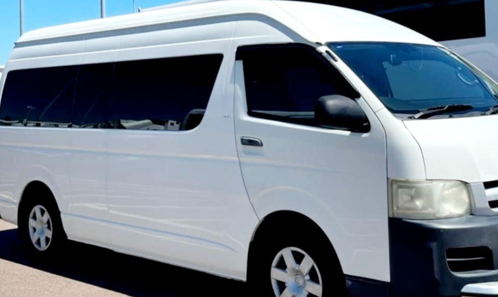 A White Van Is Parked on The Side of The Road in Front of A Brick Wall — Territory Limousine Service in Marrara, NT
