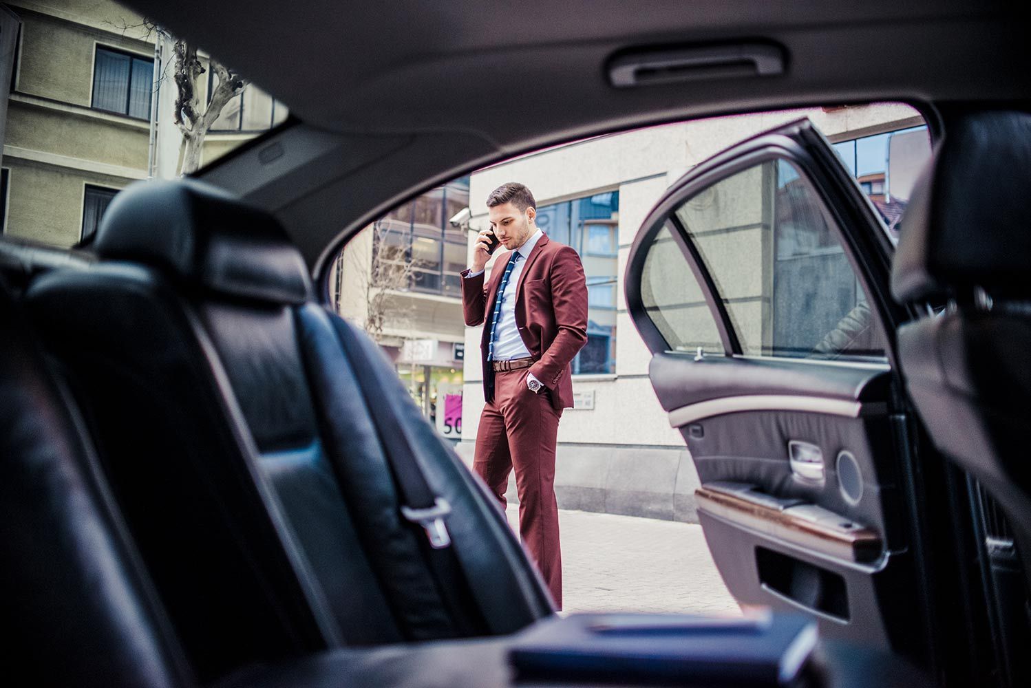 A Man in a Suit is Talking on a Cell Phone in the Back Seat of a Car — Territory Limousine Service in Marrara, NT