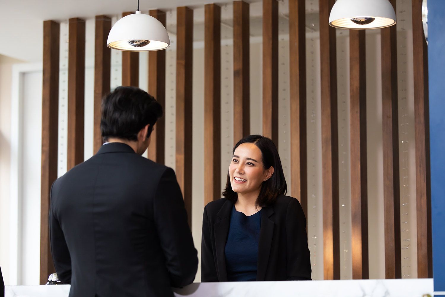 A Man is Talking to a Woman at a Hotel Reception Desk — Territory Limousine Service in Marrara, NT