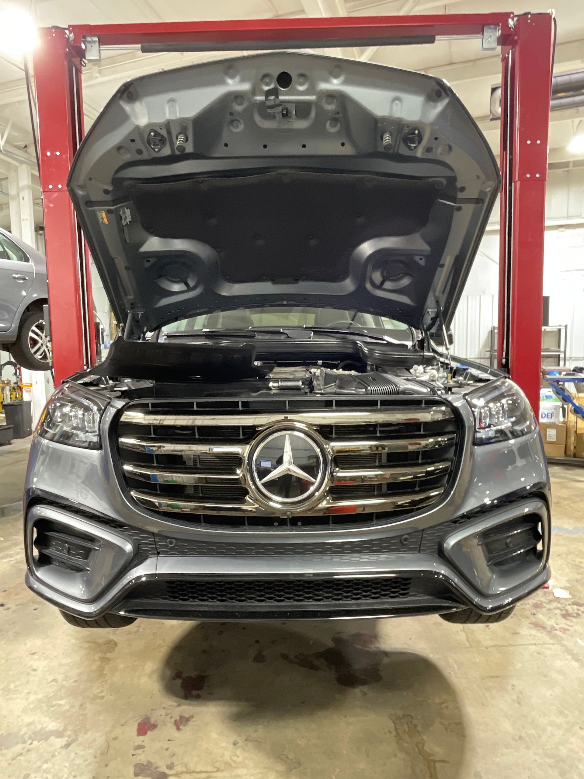 Gray Mercedes SUV with hood open, in a garage, on a lift. | Benz Tech