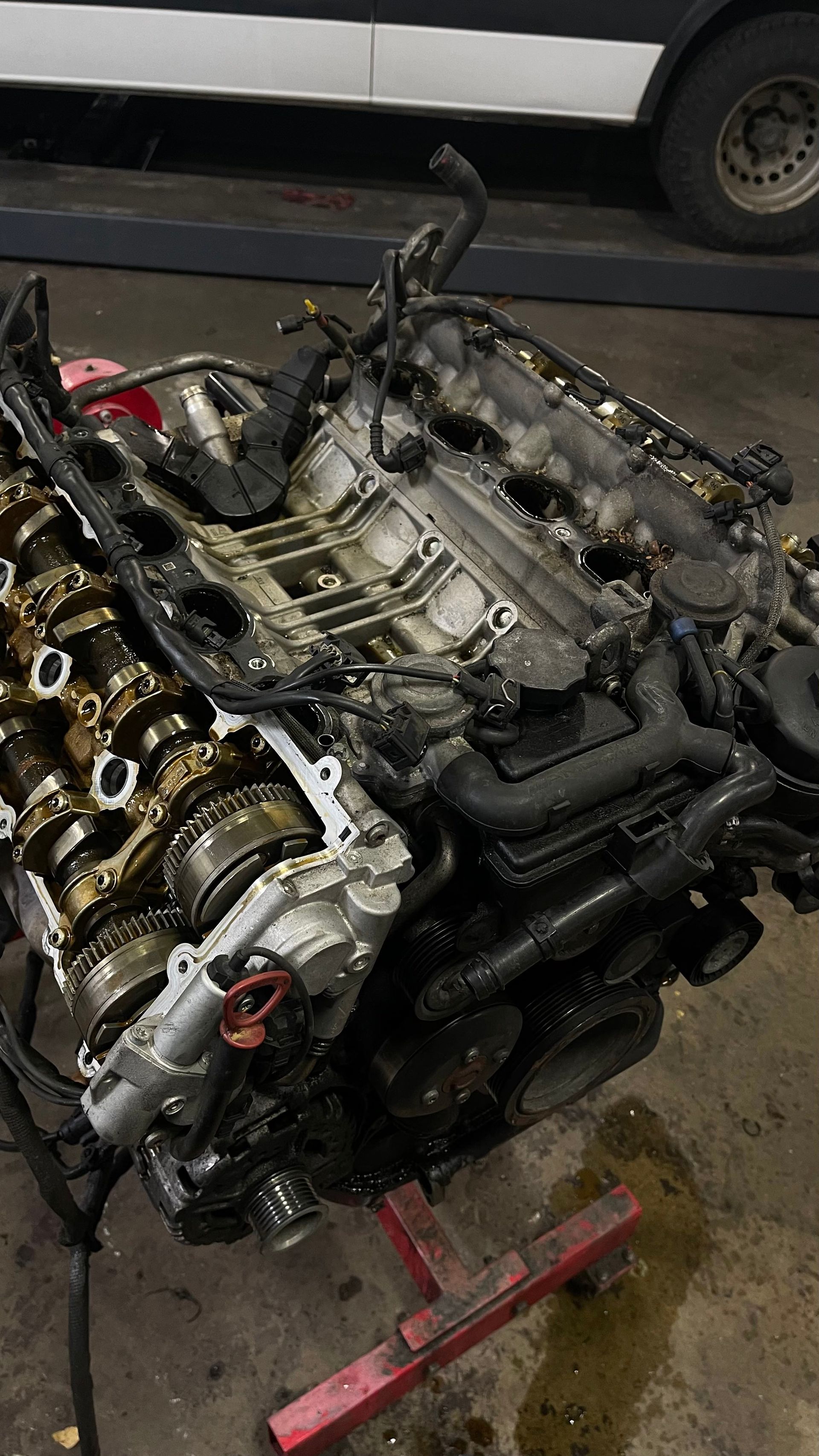 A disassembled car engine on a red stand in a garage. | Benz Tech