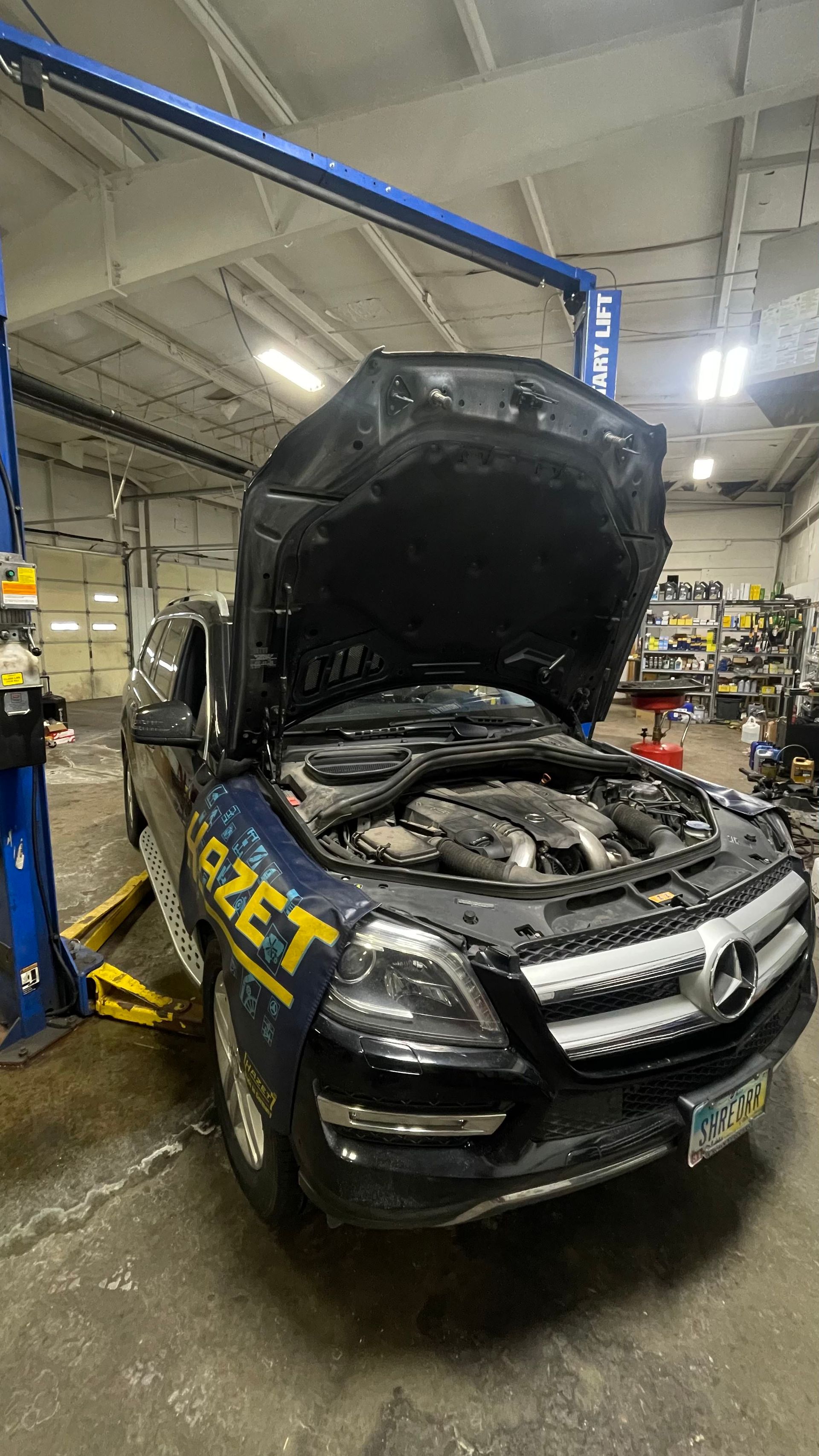 Mercedes SUV with hood open, on a lift in a garage; work being performed. | Benz Tech