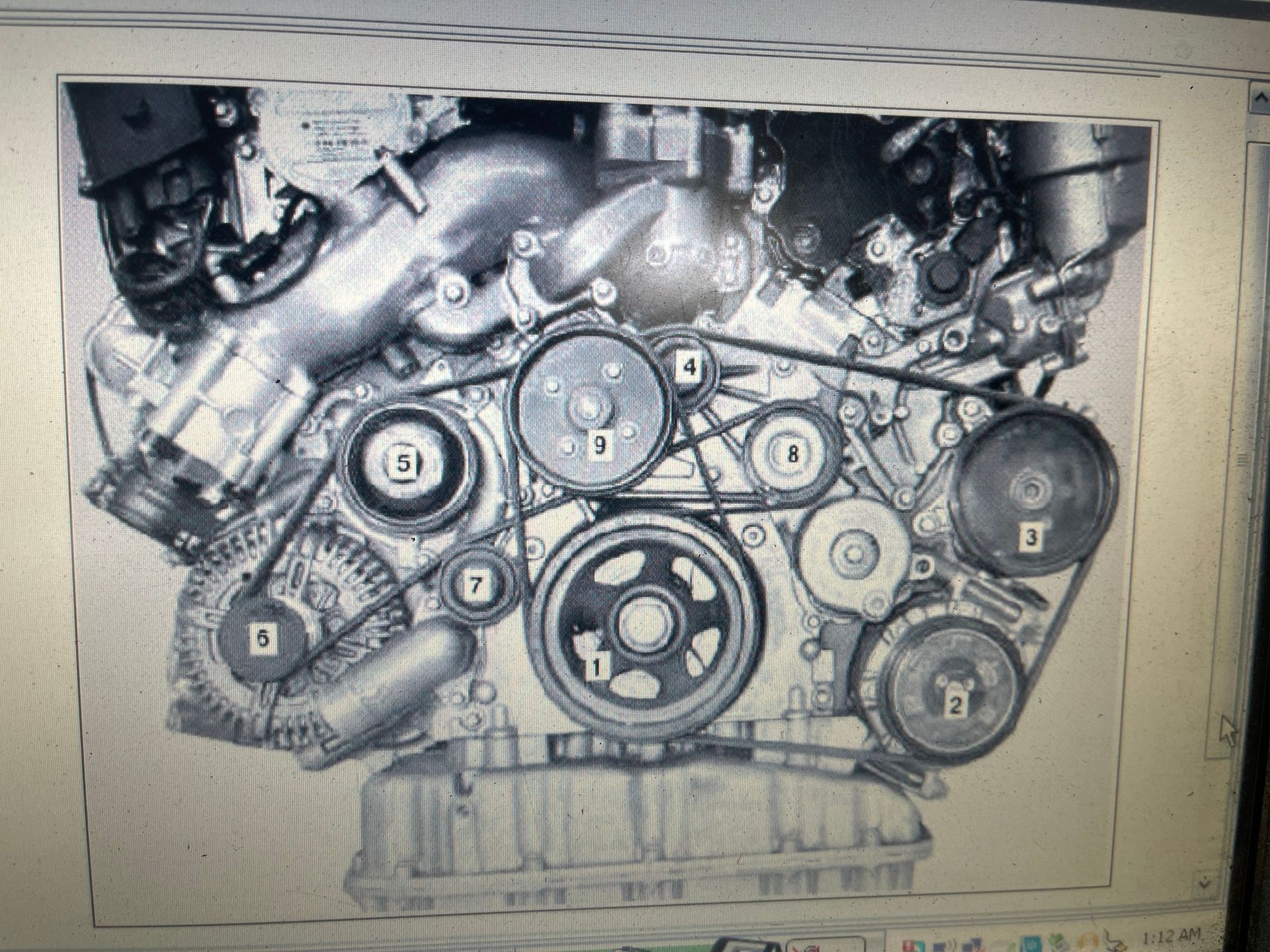 An engine with belts and pulleys labeled 1-8. Black and white photo. | Benz Tech